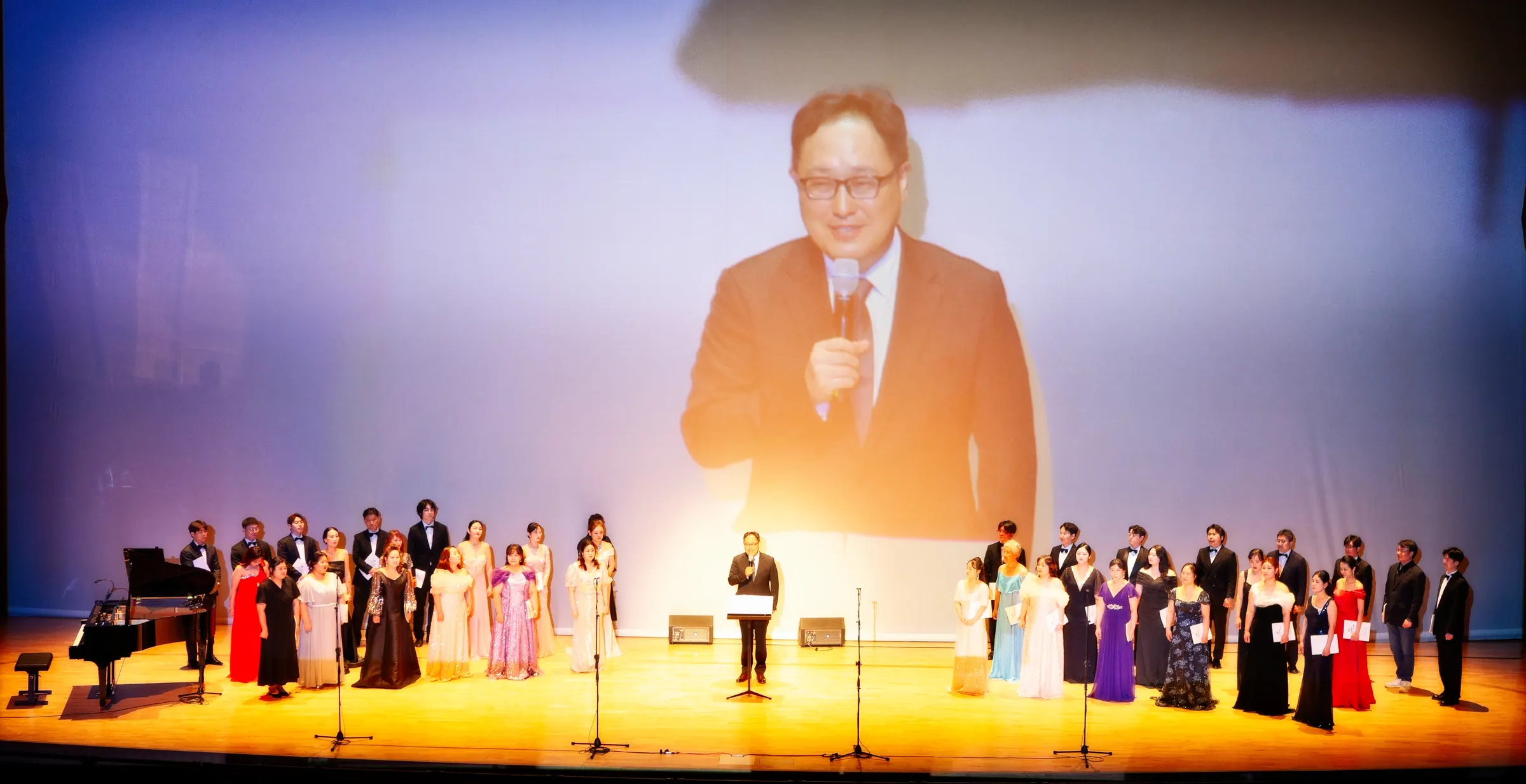 President Hwang Min-hyo giving thanks at the HTUS 70th anniversary concert, with the choir on stage
