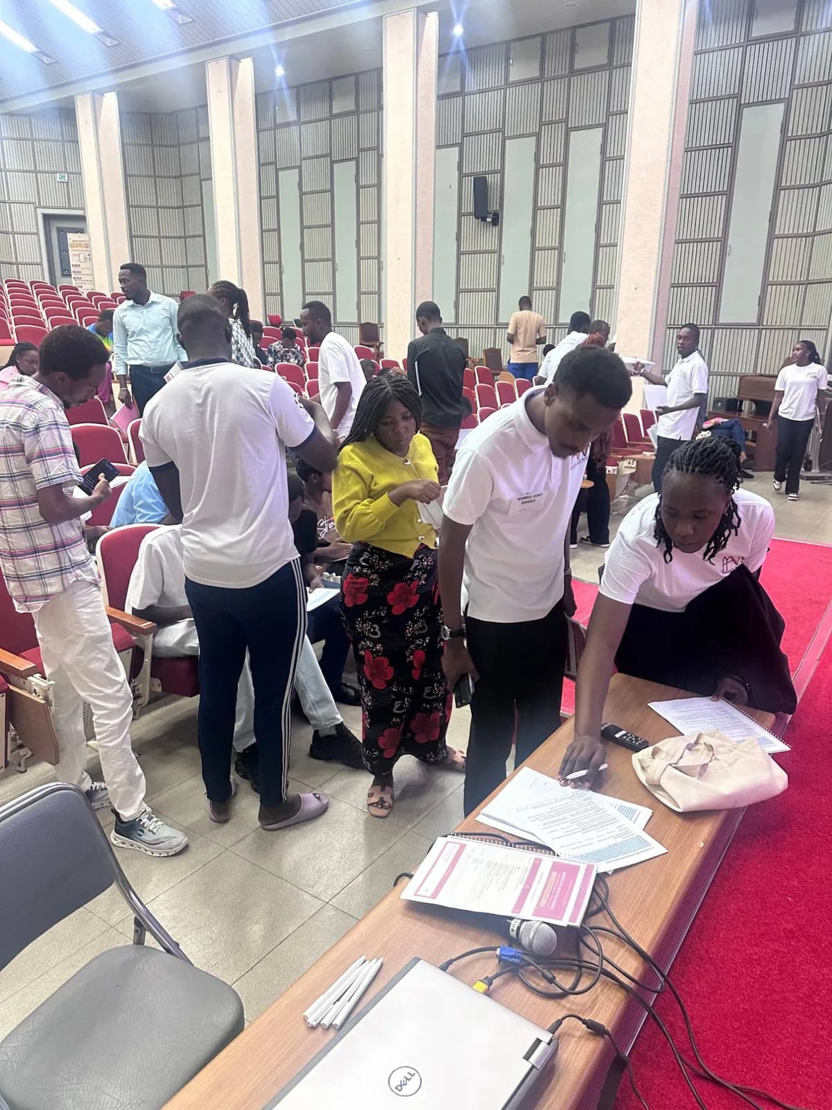 Students filling in registration forms at the front desk of the hall