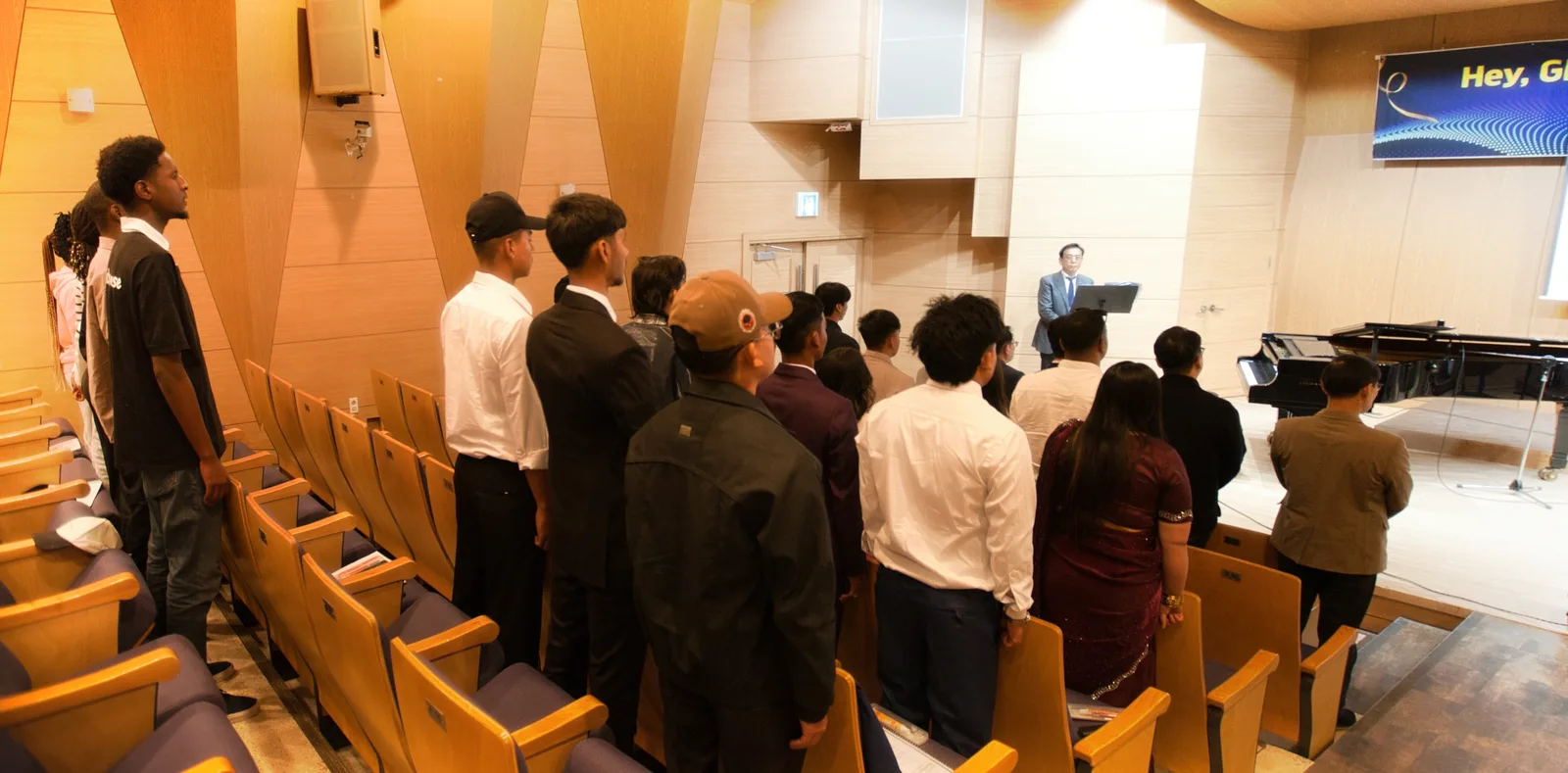 Students standing in the auditorium during the ceremony