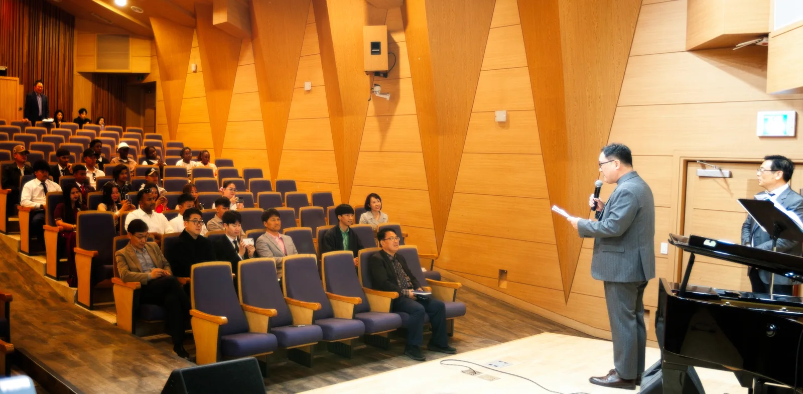 A welcome address to new students seated in the auditorium