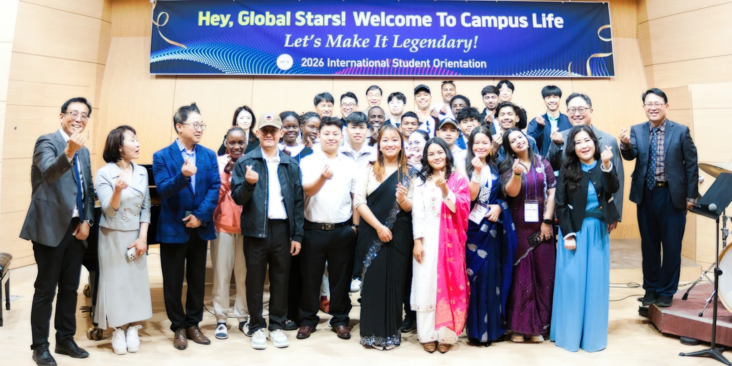 Spring 2026 orientation group photo on stage, students from Nepal in traditional dress with faculty and staff
