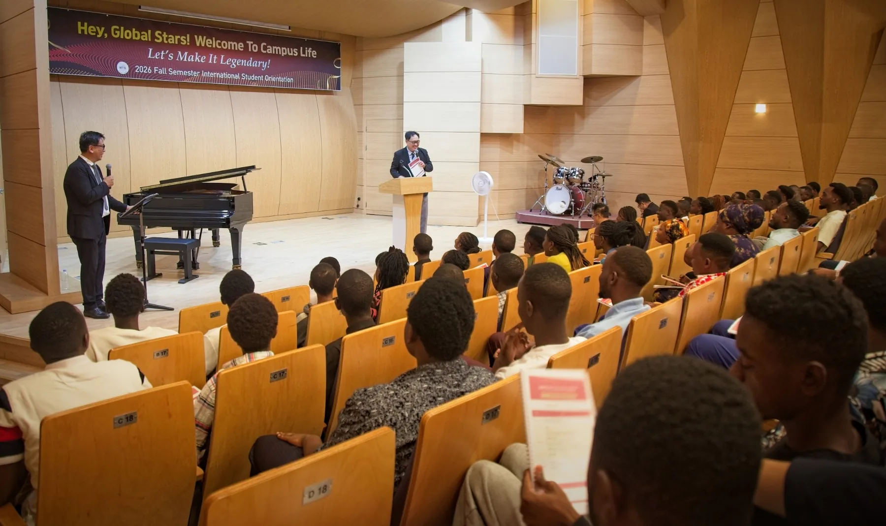 The Dean of International Affairs and the host speaking on stage under the orientation banner